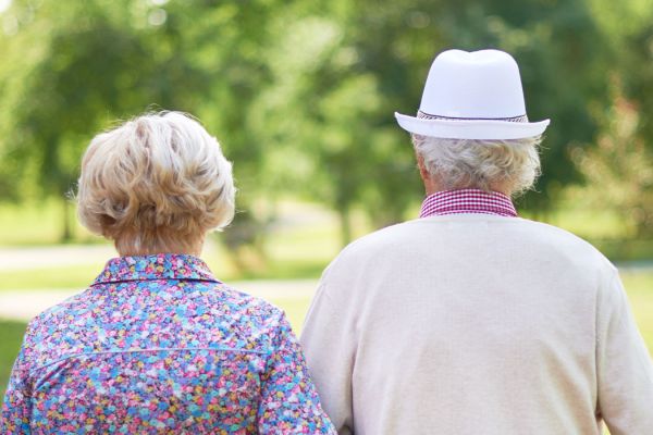 An elderly couple walking in a park.